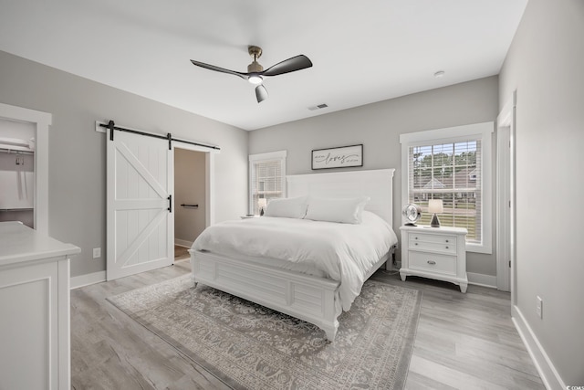 2143 Stonecrest Dr NW, Calabash, NC 28467 - bedroom featuring a barn door, light wood-type flooring, and a ceiling fan