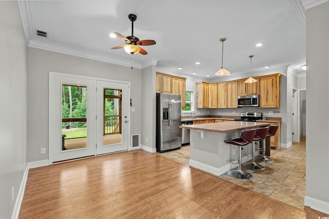 2135 Starduster Ln, Little River, SC 29566 - kitchen featuring appliances with stainless steel finishes, a ceiling fan, a kitchen bar, crown molding, and a center island