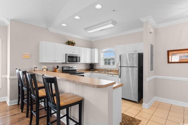 4872 Dahlia Ct Unit 305, Myrtle Beach, SC 29577 - kitchen with appliances with stainless steel finishes, a peninsula, a breakfast bar, white cabinets, and crown molding