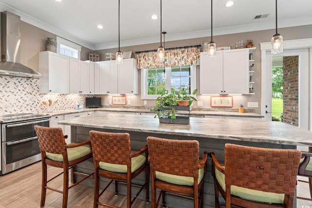 1106 Bluffton Ct, Myrtle Beach, SC 29579 - kitchen with double oven range, wall chimney range hood, white cabinets, a center island, and ornamental molding