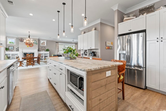 1106 Bluffton Ct, Myrtle Beach, SC 29579 - kitchen with stainless steel appliances, light wood-style floors, ornamental molding, white cabinetry, and a kitchen island