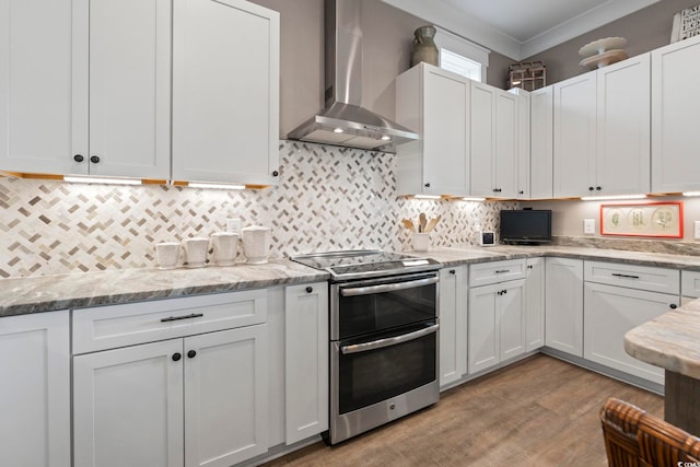 1106 Bluffton Ct, Myrtle Beach, SC 29579 - kitchen with wall chimney range hood, double oven range, white cabinetry, light wood-style floors, and crown molding