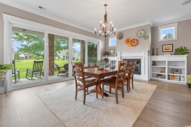 1106 Bluffton Ct, Myrtle Beach, SC 29579 - dining area featuring ornamental molding, a chandelier, a tile fireplace, and light wood-style flooring
