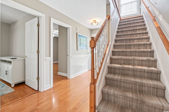 670 2nd Ave N, North Myrtle Beach, SC 29582 - stairway featuring wood finished floors, a wainscoted wall, and plenty of natural light
