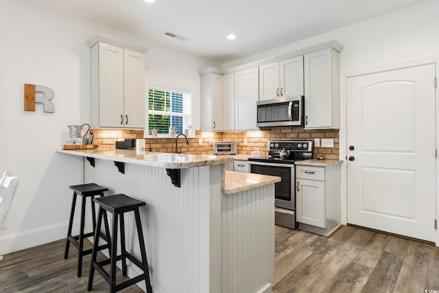 2588 Long Ave, Conway, SC 29526 - kitchen with stainless steel appliances, a kitchen breakfast bar, wood finished floors, tasteful backsplash, and a peninsula