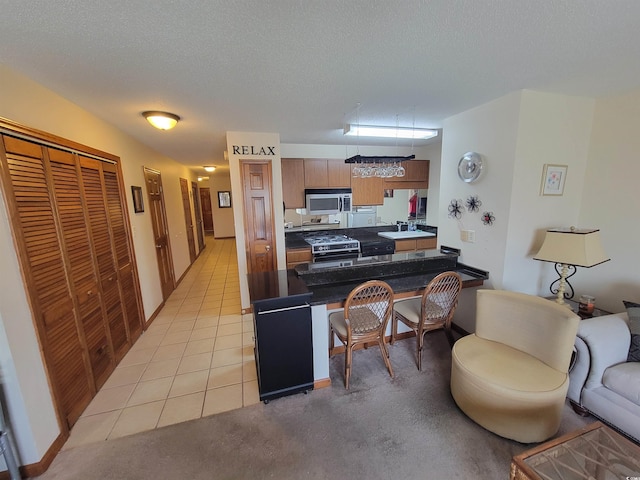207 Double Eagle Dr Unit E-1, Surfside Beach, SC 29575 - kitchen featuring black range with gas stovetop, stainless steel microwave, a peninsula, a kitchen bar, and dark countertops