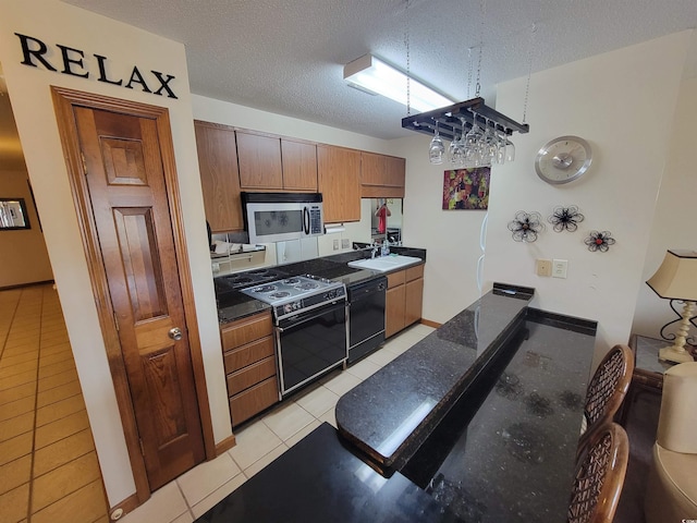 207 Double Eagle Dr Unit E-1, Surfside Beach, SC 29575 - kitchen with stainless steel microwave, range with electric stovetop, black dishwasher, dark countertops, and light tile patterned floors