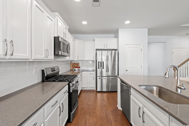 405 Spring View Ct, Little River, SC 29566 - kitchen with appliances with stainless steel finishes, white cabinetry, dark wood finished floors, light stone counters, and backsplash