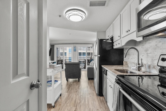 920 N Waccamaw Dr Unit 2310, Murrells Inlet, SC 29576 - kitchen with stainless steel appliances, light wood-type flooring, white cabinetry, and backsplash