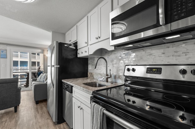 920 N Waccamaw Dr Unit 2310, Murrells Inlet, SC 29576 - kitchen featuring appliances with stainless steel finishes, light wood finished floors, backsplash, white cabinetry, and light stone countertops