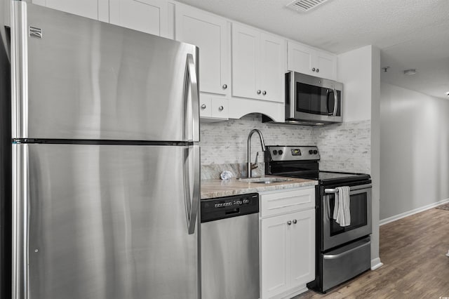 920 N Waccamaw Dr Unit 2310, Murrells Inlet, SC 29576 - kitchen featuring stainless steel appliances, tasteful backsplash, white cabinets, wood finished floors, and a textured ceiling
