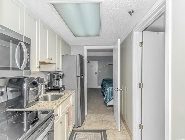 201 S Ocean Blvd Unit 616, Myrtle Beach, SC 29577 - kitchen featuring stainless steel appliances, light stone counters, light tile patterned floors, and a textured ceiling