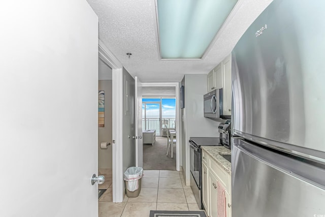 201 S Ocean Blvd Unit 616, Myrtle Beach, SC 29577 - kitchen with appliances with stainless steel finishes, a textured ceiling, light tile patterned flooring, light carpet, and light stone counters