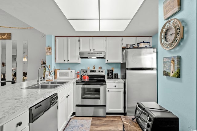 1101 2nd Ave N Unit 1501, Surfside Beach, SC 29575 - kitchen featuring appliances with stainless steel finishes, under cabinet range hood, light wood-type flooring, white cabinetry, and a peninsula