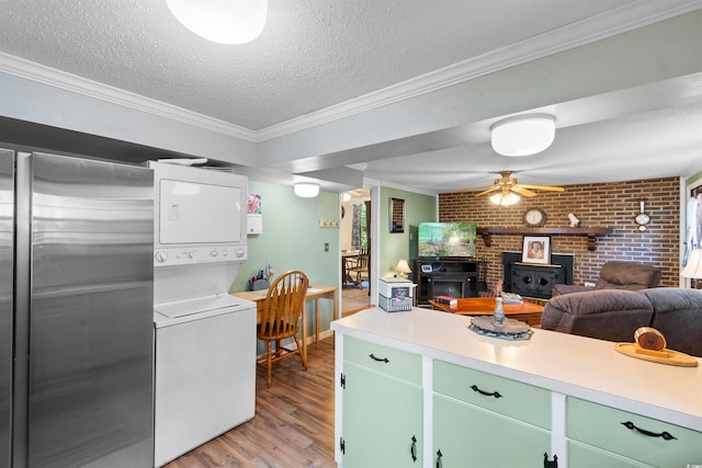 1272 Park Hill Dr, Conway, SC 29526 - kitchen featuring stacked washer / dryer, a wood stove, light wood-style flooring, light countertops, and ornamental molding