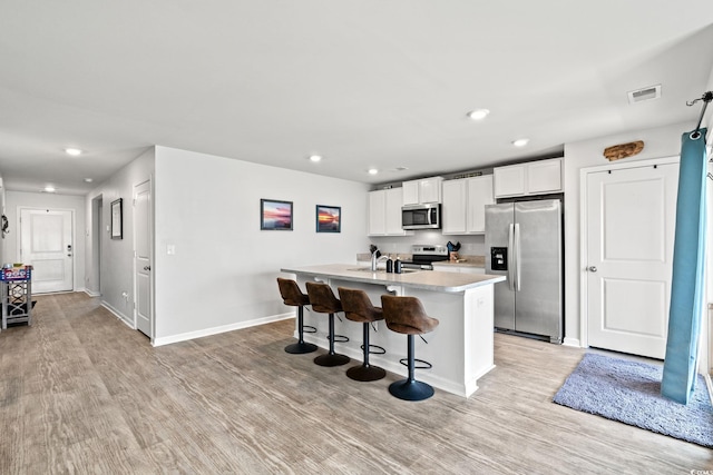821 Twickenham Loop, Longs, SC 29568 - kitchen with stainless steel appliances, light wood-style floors, a kitchen island with sink, white cabinetry, and recessed lighting