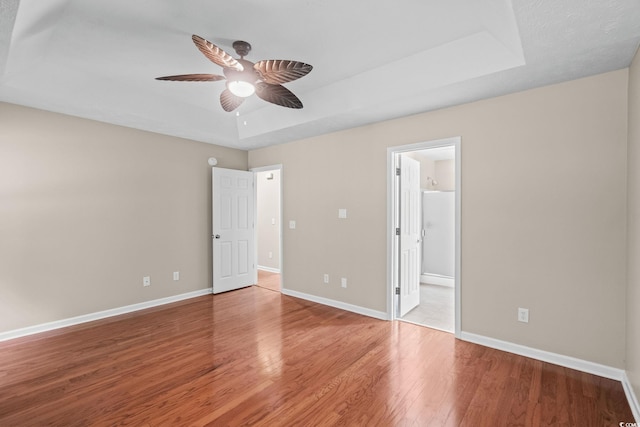 5008 Hayes Bay Ct, Murrells Inlet, SC 29576 - unfurnished bedroom with a tray ceiling, wood finished floors, connected bathroom, and a ceiling fan