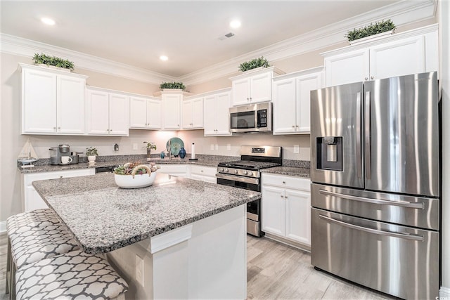 800 Monarch Dr Unit 49, Myrtle Beach, SC 29588 - kitchen with appliances with stainless steel finishes, white cabinets, light wood-type flooring, light stone counters, and crown molding