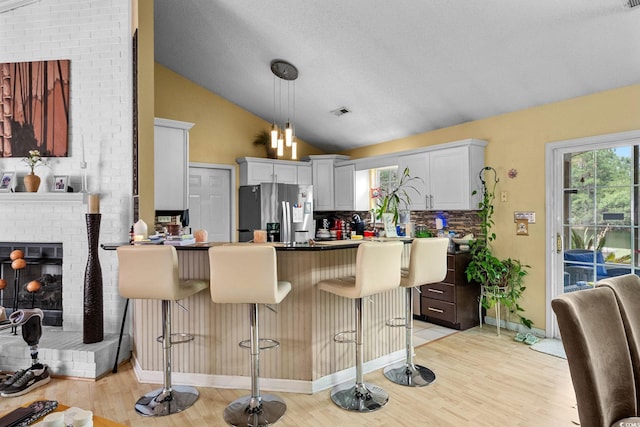 2611 Ringneck Trl, Myrtle Beach, SC 29588 - kitchen with stainless steel fridge, vaulted ceiling, a peninsula, light wood-type flooring, and tasteful backsplash
