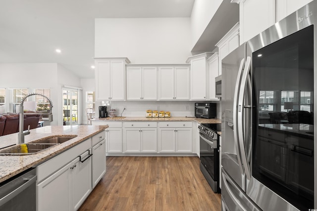 892 Harrison Mill St, Myrtle Beach, SC 29579 - kitchen with stainless steel appliances, white cabinetry, light wood-style flooring, backsplash, and light stone counters