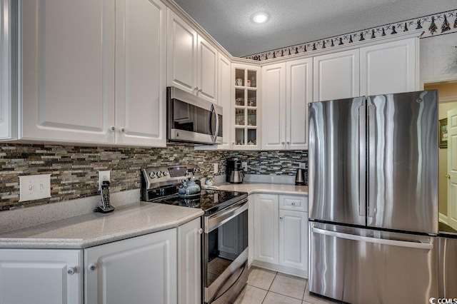 911 Tilghman Forest Dr, North Myrtle Beach, SC 29582 - kitchen with appliances with stainless steel finishes, white cabinets, backsplash, glass insert cabinets, and a textured ceiling