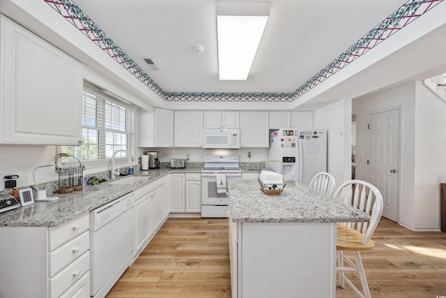 30462NDAVE N 62nd Ave N, North Myrtle Beach, SC 29582 - kitchen featuring white appliances, light wood finished floors, a breakfast bar area, a center island, and white cabinetry