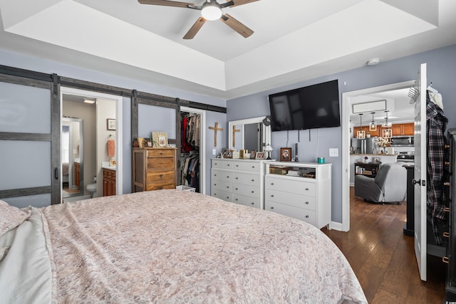 2395 Morlynn Dr, Myrtle Beach, SC 29577 - bedroom featuring a barn door, dark wood-style flooring, a closet, a walk in closet, and a tray ceiling