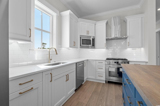 8148 Living Tide Dr, Myrtle Beach, SC 29572 - kitchen with appliances with stainless steel finishes, wall chimney range hood, blue cabinetry, white cabinetry, and light wood finished floors