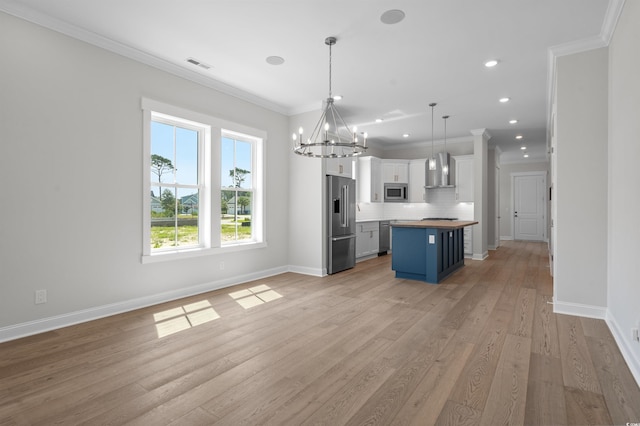 8148 Living Tide Dr, Myrtle Beach, SC 29572 - kitchen with stainless steel appliances, wall chimney exhaust hood, a chandelier, open floor plan, and white cabinetry