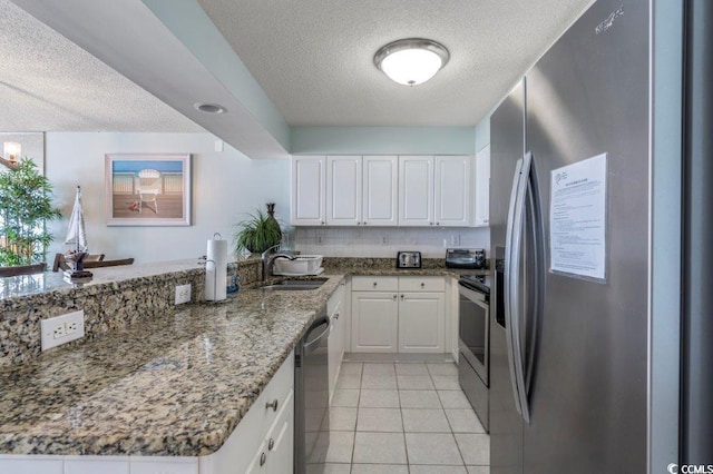 5404 N Ocean Blvd Unit 11-D, North Myrtle Beach, SC 29582 - kitchen featuring appliances with stainless steel finishes, a textured ceiling, a peninsula, white cabinetry, and light tile patterned flooring
