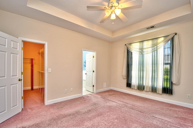 501 Painted Duck Ct, Myrtle Beach, SC 29588 - unfurnished bedroom with a tray ceiling, carpet, a spacious closet, ensuite bathroom, and a ceiling fan