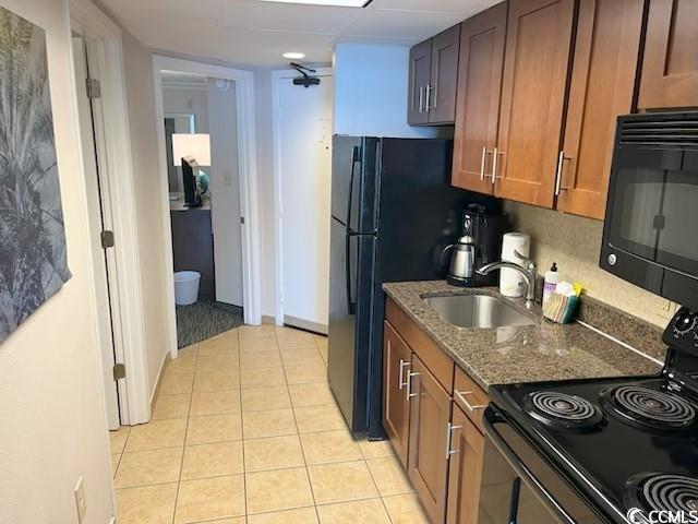 1105 S Ocean Blvd Unit 136, Myrtle Beach, SC 29577 - kitchen featuring black appliances, brown cabinets, dark stone countertops, and light tile patterned flooring