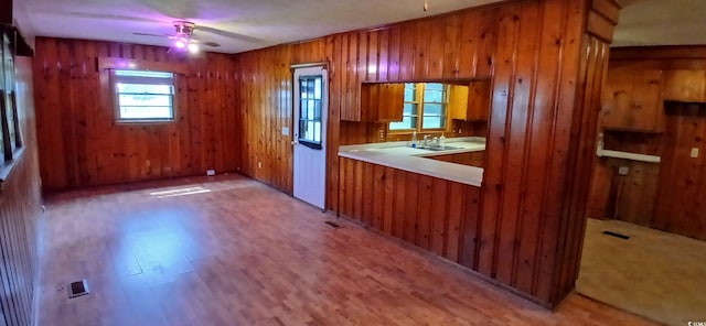 1206 French Rd, Mullins, SC 29574 - kitchen featuring brown cabinets, ceiling fan, light wood-style flooring, light countertops, and wood walls