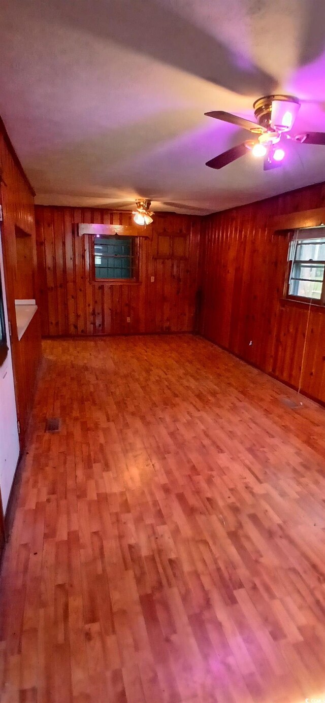 1206 French Rd, Mullins, SC 29574 - unfurnished living room featuring wood walls, wood finished floors, and a ceiling fan