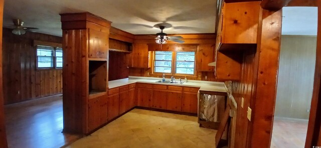 1206 French Rd, Mullins, SC 29574 - kitchen featuring ceiling fan, brown cabinetry, wood walls, and healthy amount of natural light