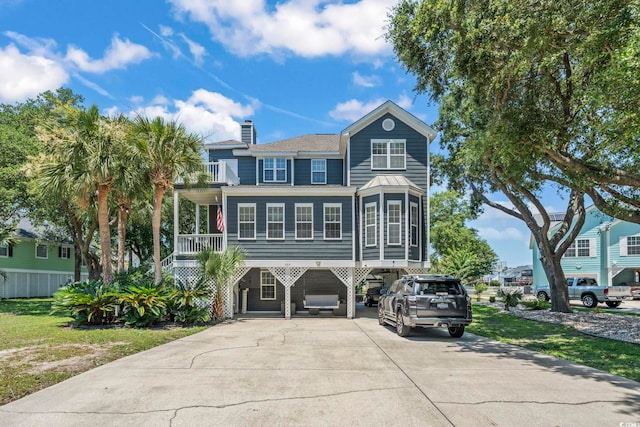 709 Triple Oak Ln, Garden City Beach, SC 29576 - raised beach house with driveway, a carport, a balcony, and a chimney