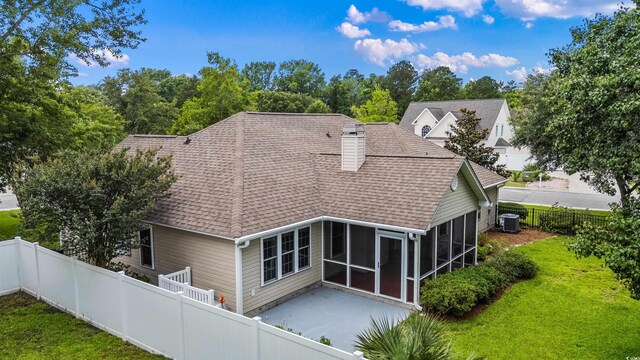 104 Ashton Cir, Myrtle Beach, SC 29588 - back of house featuring roof with shingles, a sunroom, a patio, a fenced backyard, and a chimney