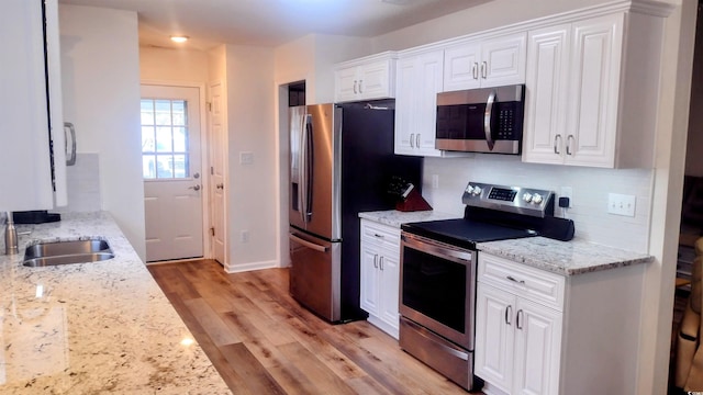 219 Birdie Way, Longs, SC 29568 - kitchen featuring appliances with stainless steel finishes, white cabinetry, light wood-type flooring, backsplash, and light stone countertops