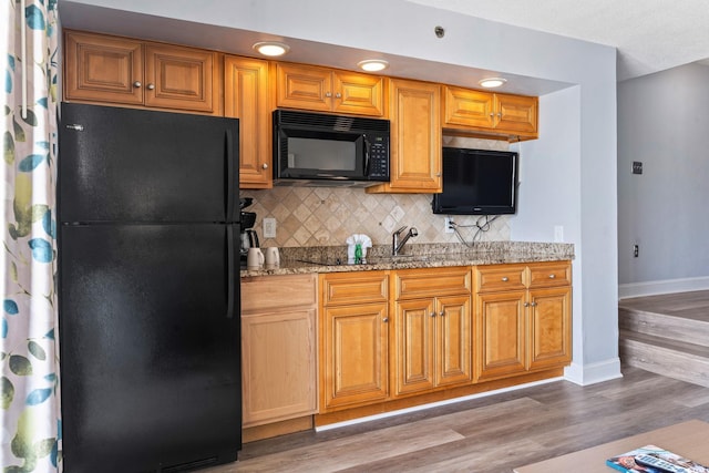 4800 S Ocean Blvd Unit 1008, North Myrtle Beach, SC 29582 - kitchen with black appliances, tasteful backsplash, wood finished floors, and light stone counters