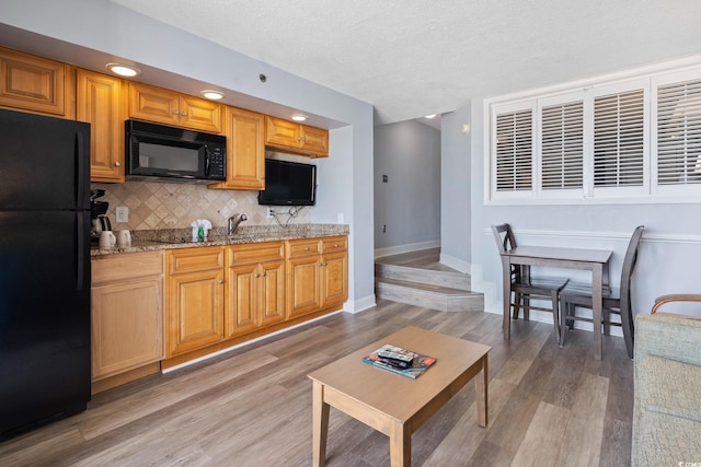 4800 S Ocean Blvd Unit 1008, North Myrtle Beach, SC 29582 - kitchen with black appliances, backsplash, light wood-style flooring, light stone countertops, and a textured ceiling