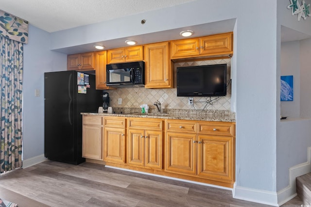 4800 S Ocean Blvd Unit 1008, North Myrtle Beach, SC 29582 - kitchen with black appliances, backsplash, light wood-style floors, and light stone counters