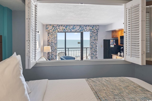 4800 S Ocean Blvd Unit 1008, North Myrtle Beach, SC 29582 - bedroom featuring freestanding refrigerator, a water view, access to exterior, and a textured ceiling