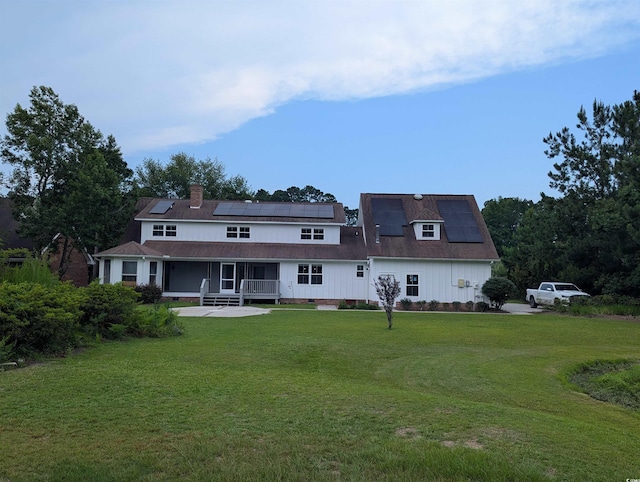 4719 National Dr, Myrtle Beach, SC 29579 - rear view of house featuring roof mounted solar panels, a lawn, a porch, and a chimney