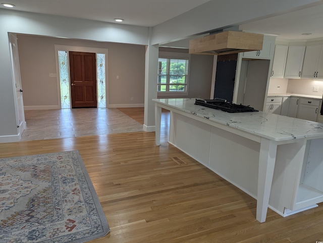 4719 National Dr, Myrtle Beach, SC 29579 - kitchen with gas stovetop, light wood finished floors, light stone countertops, exhaust hood, and white cabinetry