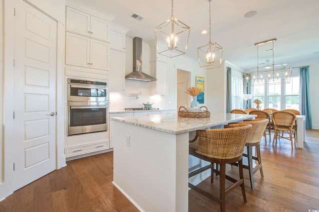 1627 Sayebrook Pkwy, Myrtle Beach, SC 29588 - kitchen with wall chimney exhaust hood, a chandelier, appliances with stainless steel finishes, dark wood finished floors, and a center island with sink
