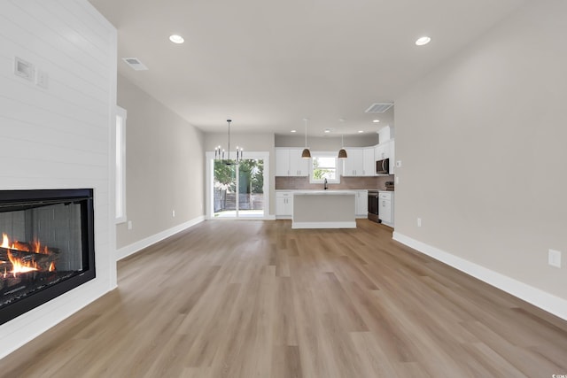 4329 Landing Rd, Little River, SC 29566 - unfurnished living room with a large fireplace, light wood finished floors, recessed lighting, and a chandelier