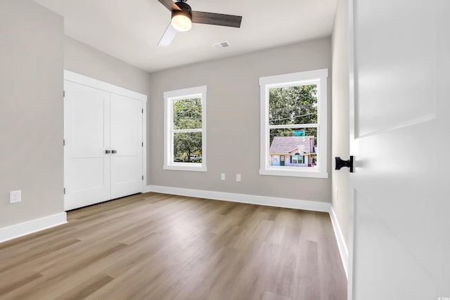 4329 Landing Rd, Little River, SC 29566 - unfurnished bedroom with multiple windows, light wood-style floors, a ceiling fan, and a closet