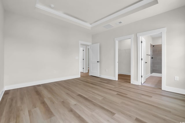 4329 Landing Rd, Little River, SC 29566 - unfurnished bedroom featuring a raised ceiling, a walk in closet, ornamental molding, light wood-style flooring, and a closet