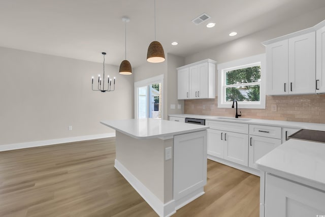 4329 Landing Rd, Little River, SC 29566 - kitchen with light wood-type flooring, backsplash, a center island, light countertops, and white cabinets