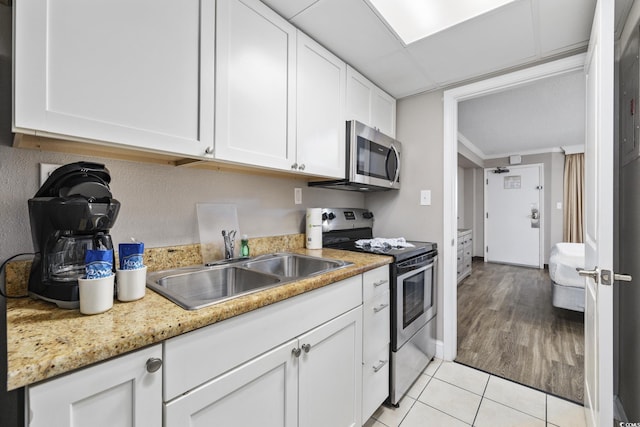 6900 N Ocean Blvd Unit 834, Myrtle Beach, SC 29572 - kitchen with appliances with stainless steel finishes, white cabinetry, and light tile patterned flooring